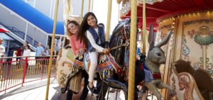 Girl and mother riding on horse on carousel