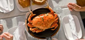 Big orange Dungeness crab on marble table with white napkins and plates